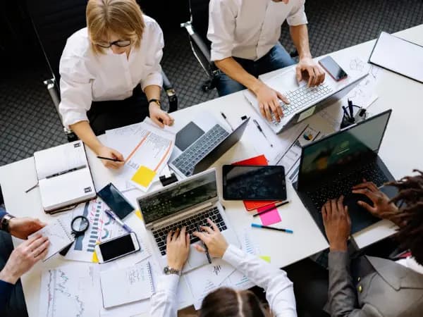 people around a cluttered desk in the office